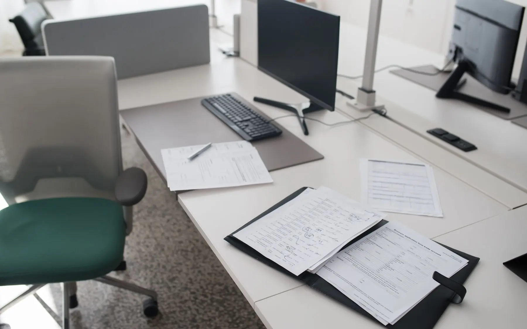 Puesto de trabajo de una oficina con documentos impresos sobre la mesa y un monitor